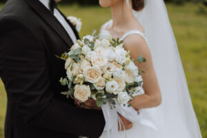 The groom hugs the bride and the bride holds a wedding bouquet