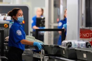 TSA agent pushes bins along at a security checkpoint