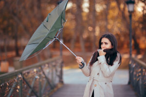 A girl fighting the wind while holding an umbrella