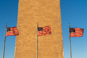 Washington Monument at sunset, during the fall, with American flags blowing in the wind