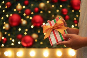 Christmas gift box with gold ribbon in man hands surprise giving to his love person