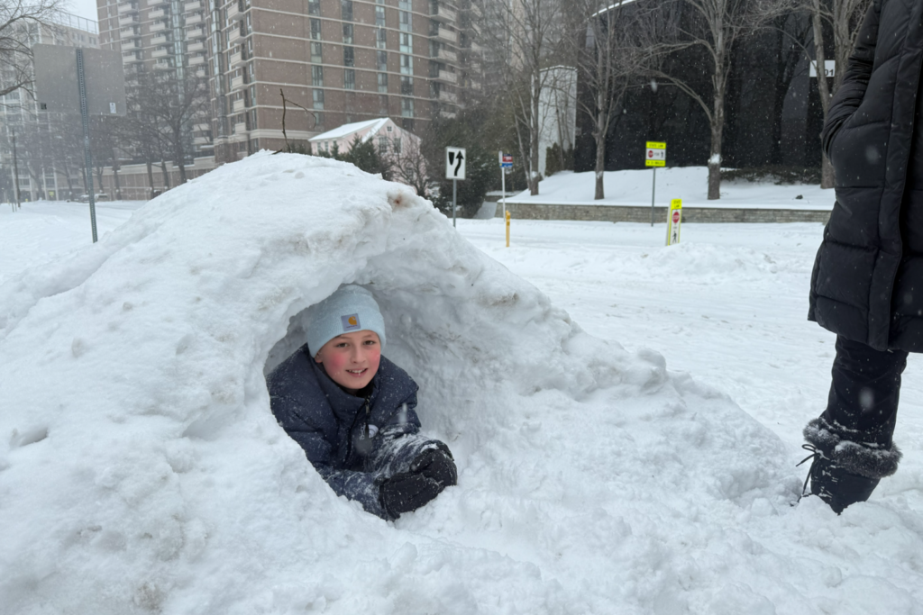 A young boy sits in a fort built out of snow in the D.C. area on Sunday, Jan. 25, 2026.