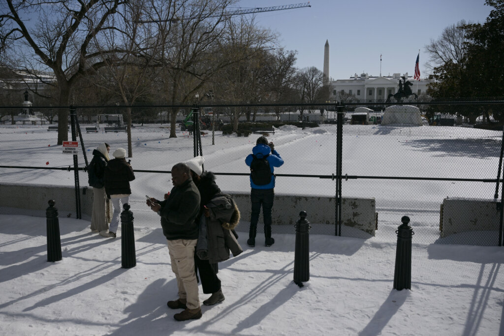 Tourists take pictures of the White House behind a security fence on January 27, 2026. Perilously cold temperatures threatened millions of Americans in the wake of a sprawling winter storm. A frigid, life-threatening Arctic air mass could delay recovery as municipalities from New Mexico to Maine tried to dig out following the storm, which dropped a vicious cocktail of heavy snow and wind along with freezing rain and sleet. (Photo by Oliver Contreras / AFP via Getty Images)