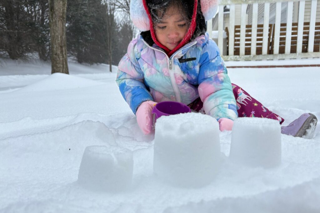 A little girl builds a structure in the snow in Germantown, Maryland, on Sunday, Jan. 25, 2026.