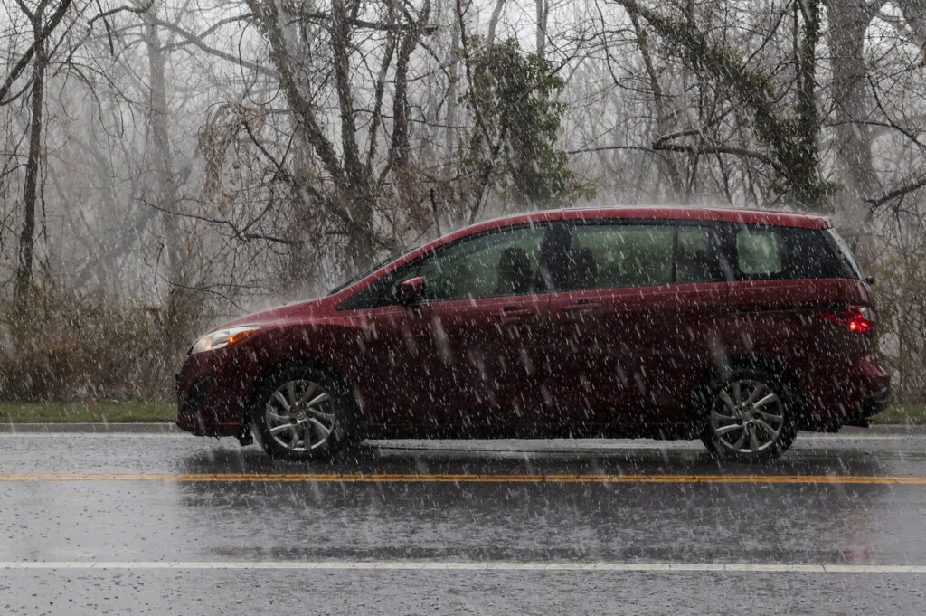 A red van drives through rain on March