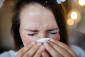 Woman rubbing nose while having a flue at home.
