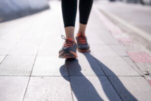 Person's,Legs,And,Feet,Wearing,Sneakers,,Walking,On,A,Pavement