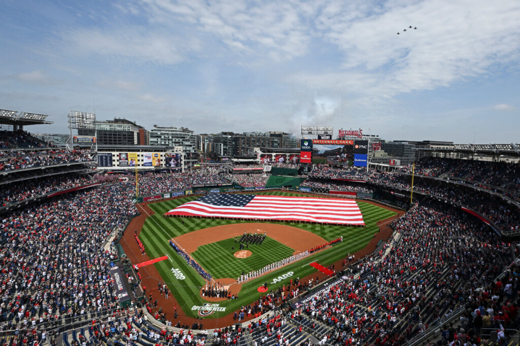 An American flag is held across the field during the national anthem