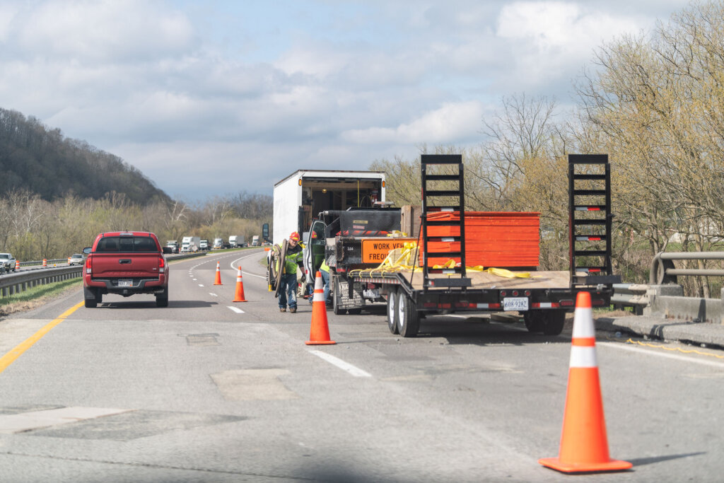 Highway road in Virginia with construction truck car by site with workers working by traffic cones