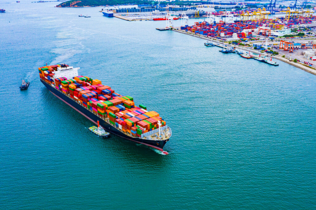 A cargo ship loaded with containers is sailing out of the port