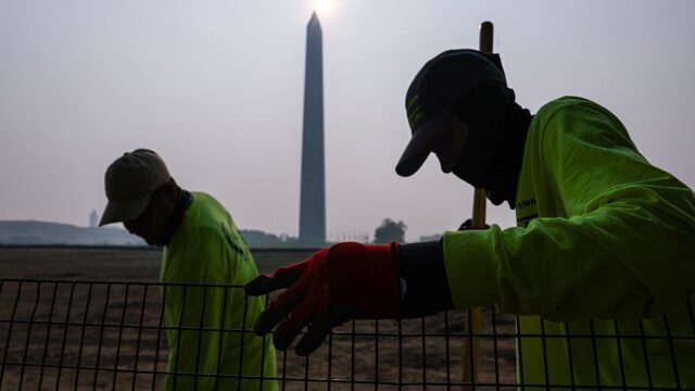 Workers on lawn of Washington Monument with hazy skies