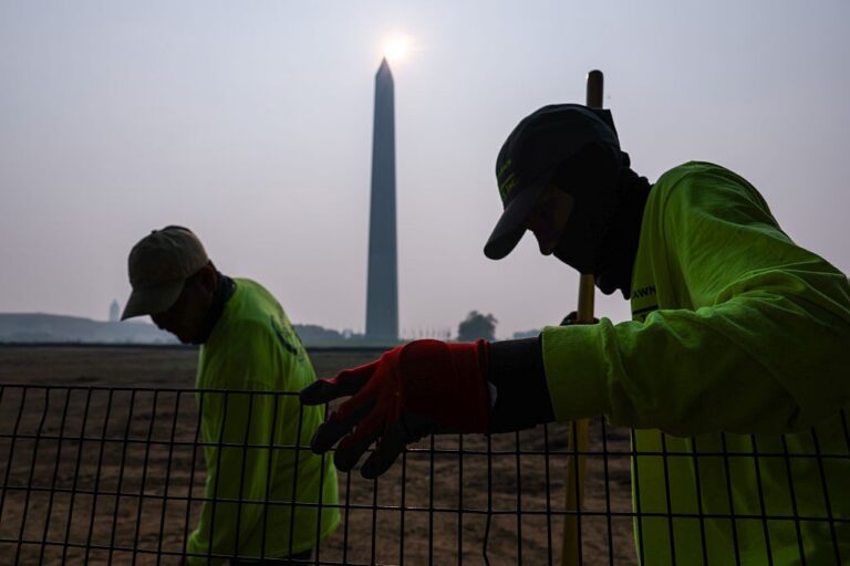 Workers on lawn of Washington Monument with hazy skies