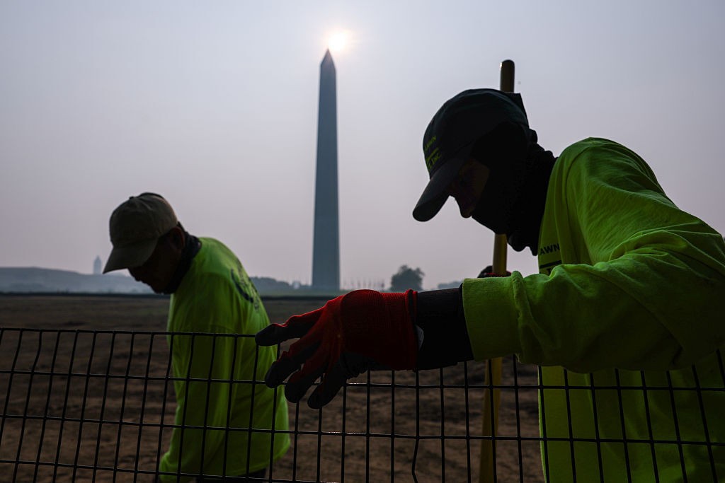 Workers on lawn of Washington Monument with hazy skies